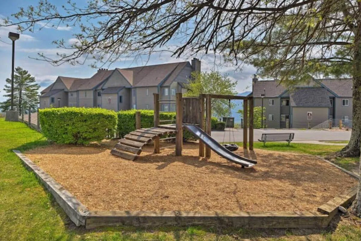 A cheerful outdoor playground set amidst greenery, including a slide and swing set. The playground is buzzing with the potential for children's laughter and family fun, framed by trees and open outdoor space.