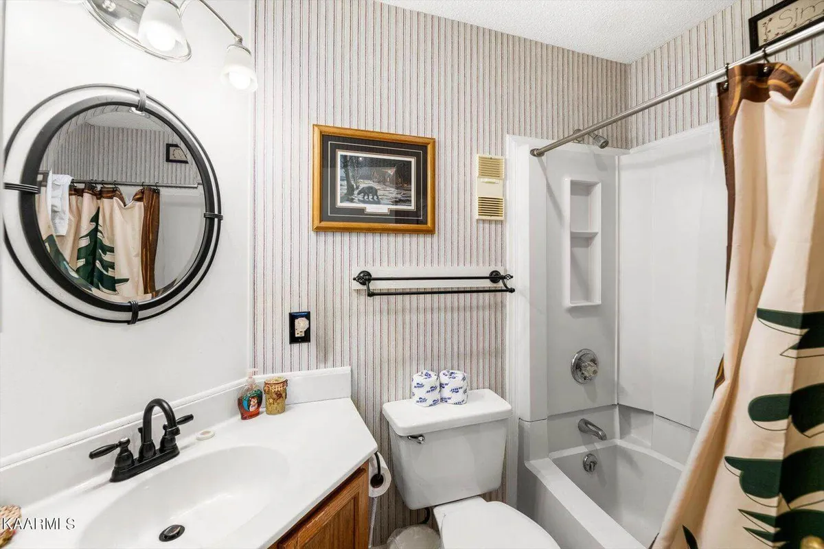 A spa-inspired bathroom featuring a large mirror, sleek sink, bathtub, framed paintings, and plush towels. The overall look is fresh, inviting, and practical for daily rituals and relaxation.