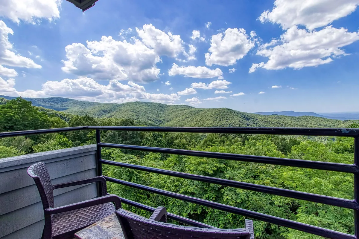 A tranquil balcony setting overlooking a sweeping mountain range, with comfortable seating ideally placed for taking in the views. The scene exudes peacefulness, making it perfect for quiet moments, morning coffee, or sunset cocktails while immersed in nature.