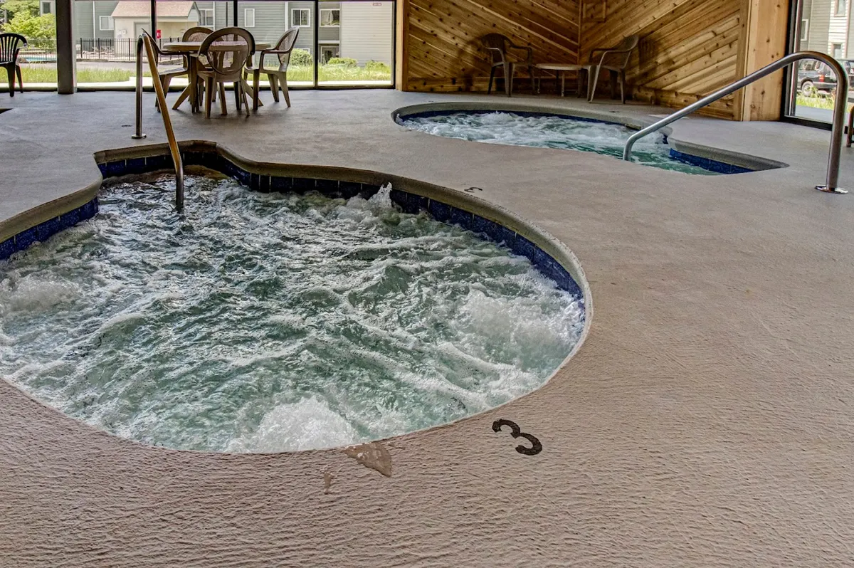 An inviting indoor spa area featuring hot tubs set against textured wooden walls, offering a calm and rejuvenating atmosphere. The seating area suggests a space perfect for relaxation after a day of adventure.
