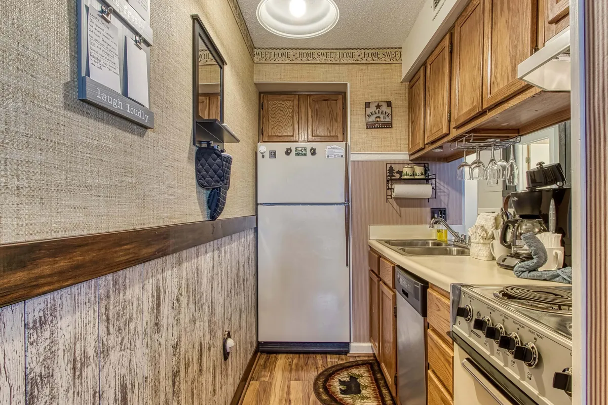 A stylish kitchen featuring a refrigerator, stove, sink, and decorative wall art, with ample kitchen accessories visible. The environment is bright and inviting, clearly reflecting recent upgrades and modern appliances.