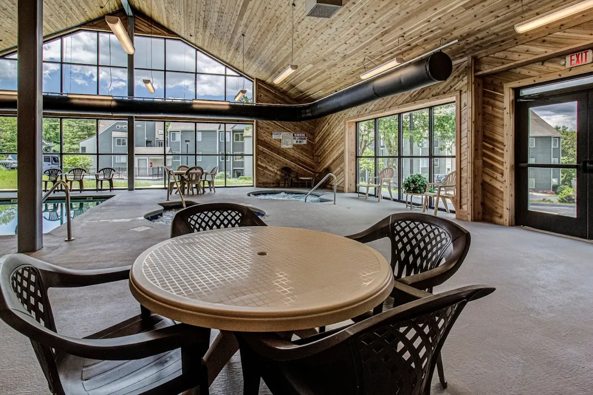 An inviting indoor pool and hot tub area with large windows letting in natural light and offering glimpses of the outdoors. The space features a wooden ceiling and comfortable seating for relaxation after a day of exploration.